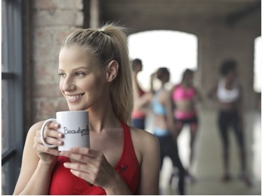 Woman holding a mug near a gym window.