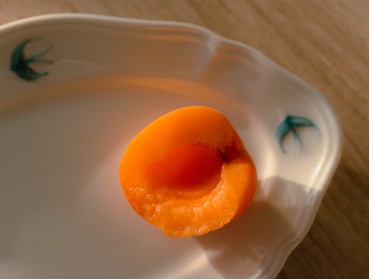 Fresh apricot on a plate in warm sunlight.